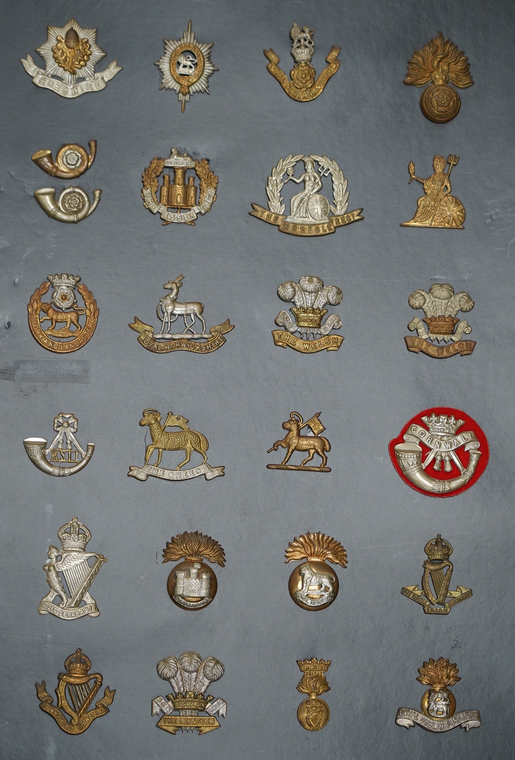 A collection of fifty-eight military cap badges, plus a few shoulder titles, mounted on four boards including; 26th Hussars, Inniskilling Regiment, 3rd Dragoon Guards, the Cheshire Regiment, Loyal North Lancashire, the N